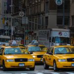 yellow taxi cab on road near white concrete building during daytime